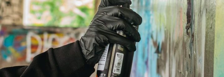 An individual holding a spray paint can, ready to create graffiti art on a wall.