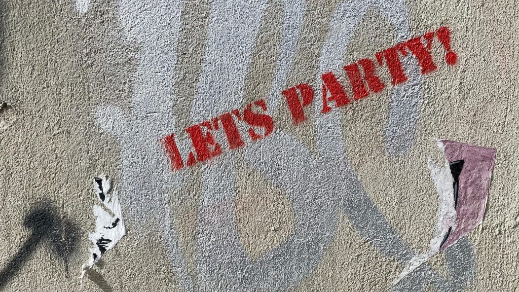 A graffiti stencil with the message 'Let's Party!' painted on a surface, conveying a sense of celebration.